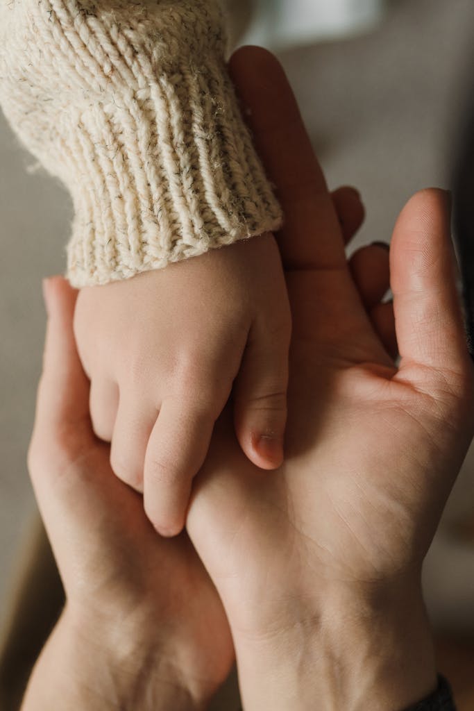 Intimate close-up of a child and adult holding hands, showing warmth and care.